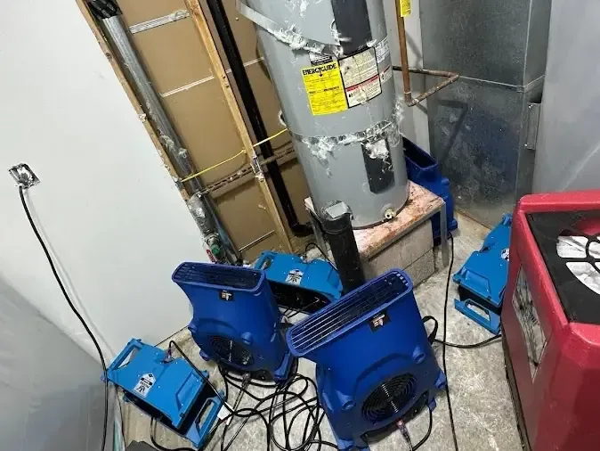 Air movers and a dehumidifier drying a water heater closet