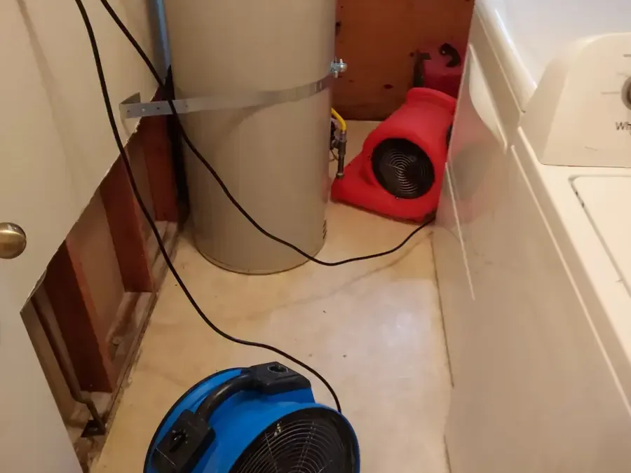 Air movers drying a laundry area with the wall opened behind the washer, an appliance leak dry-out