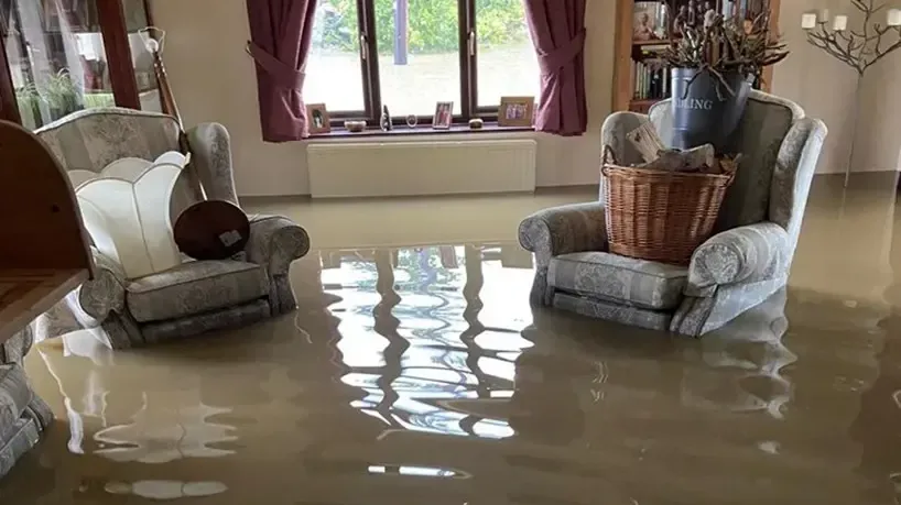 Floodwater standing in a living room around armchairs, storm flood cleanup