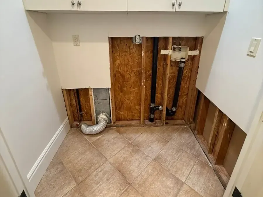Laundry wall opened around a washer box after a supply line leak