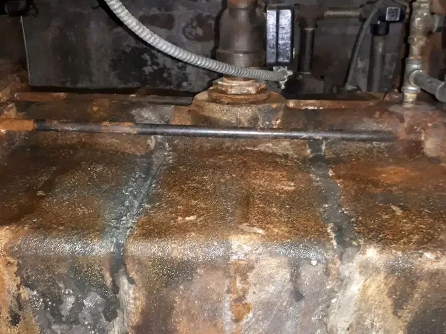 Rusted, leaking base of an old water heater tank